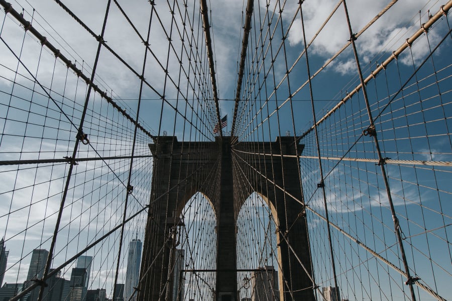 symetrical photo looking up at the arches and wires of Brooklyn Bridge