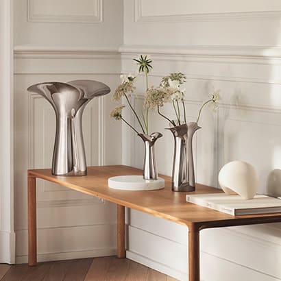 small large and medium vases in mirror polished stainless steel with flowers on a table in the lobby from the bloom botanica collection by georg jensen