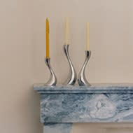 Still life image of mirror polished stainless steel candleholders with candles from the Cobra collection