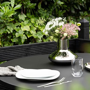 Sky and Cobra table setting items from Georg Jensen displayed on a garden table