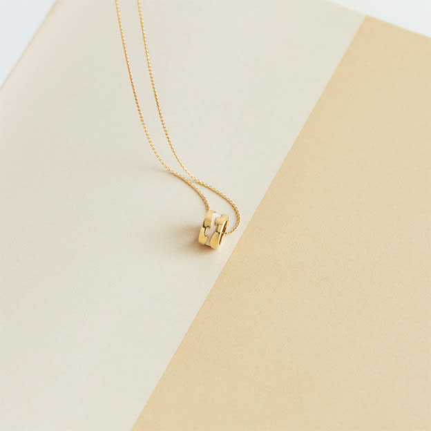 pendant in 18 karat yellow gold and warm white HyCeram on model from the fusion collection designed by Nina Koppel