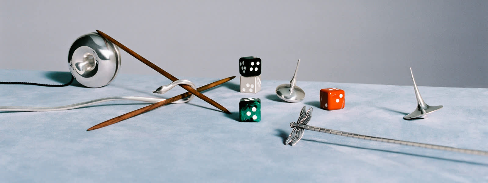 Spinning top, yo-yo, dice, and cocktail stirrer in sterling silver, and Mikado in sterling silver and walnut wood, from Georg Jensen.