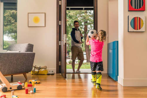 daughter carrying soccer ball towards father