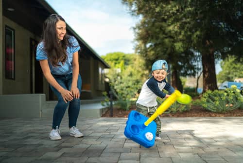 boy hitting teeball with mom