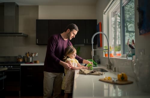 Father helps daughter rinse vegetables