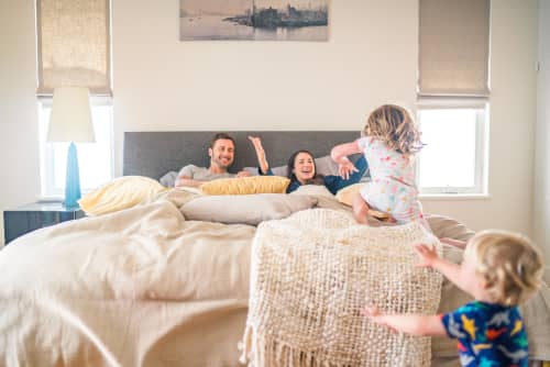 Family playing in bed son climbing on bed