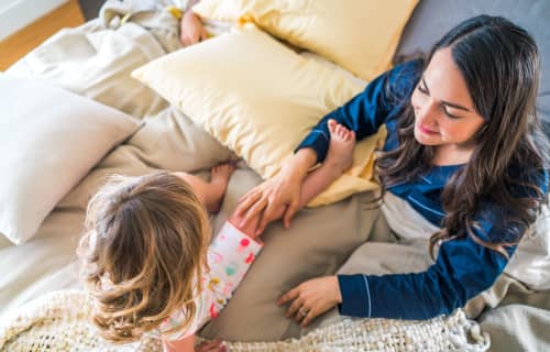 Mother and daughter playing in bed