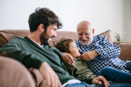 grandfather, father and son sitting on couch