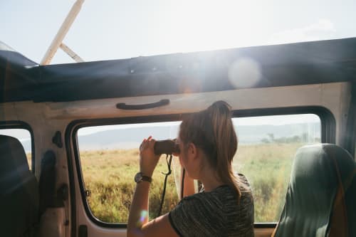 Woman looking out of car window with binoculars