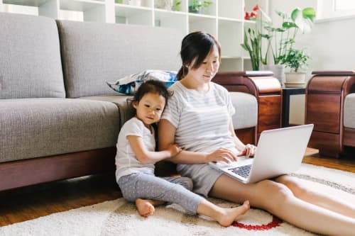 Mother and daughter sitting on the ground with laptop