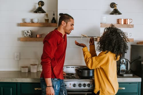 Young couple making pasta together and tasting it