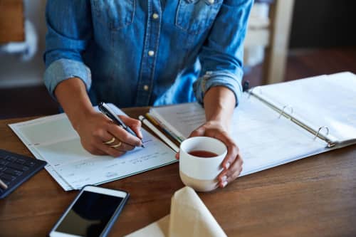 Woman at desk writing in a notebook