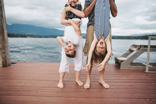 Parents Hanging Two Kids Upside Down On The Dock At The Lake