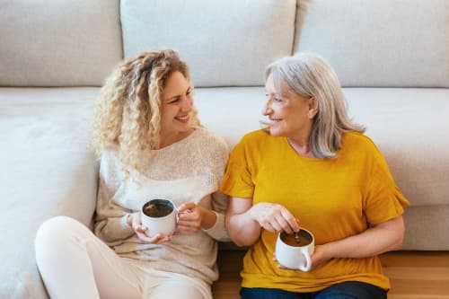 grown mother and daughter drinking coffee