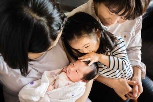 Mother, daughter and grandmother holding new baby