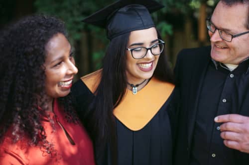 parents smiling at daughter during college graduation