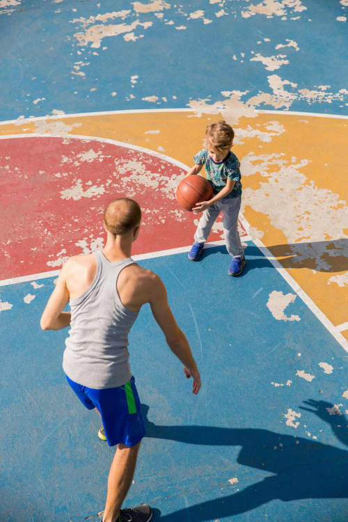 Kid playing basketball with dad