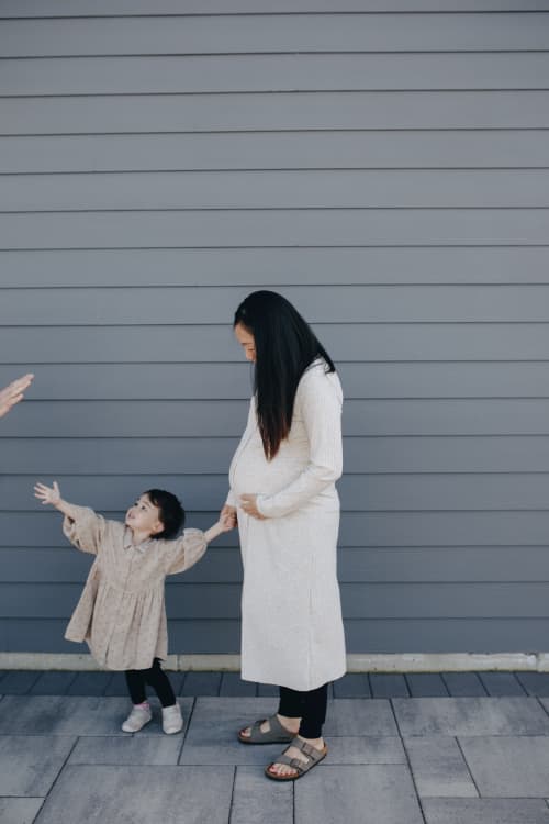 pregnant mother holding toddler's hand