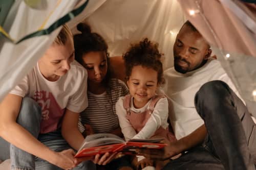 Parents reading to daughters in tent