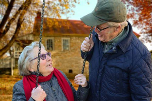 older couple on swing in park