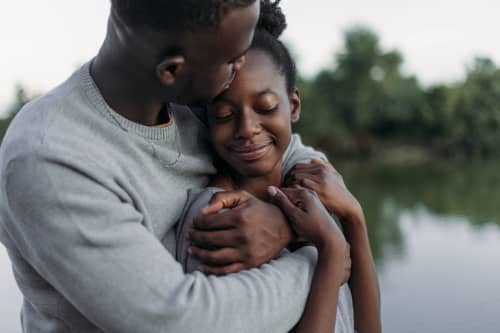 man kissing woman on forehead