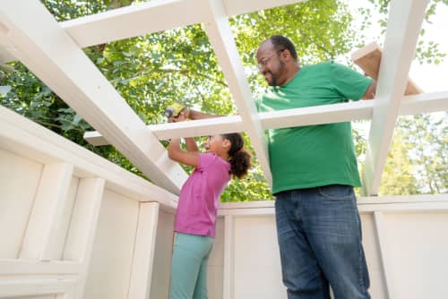 Dad helping daughter build wood structure outside