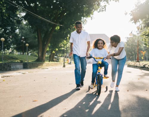 moms and dad helping daughter ride bike