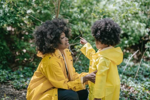 mom and daughter standing in garden in rain jackets