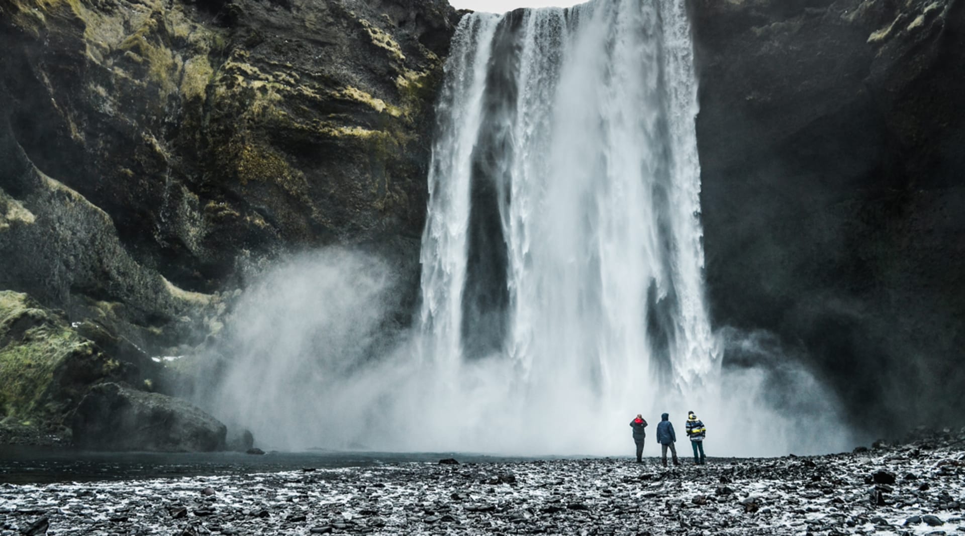 Skogafoss waterfall with people standing next to falls