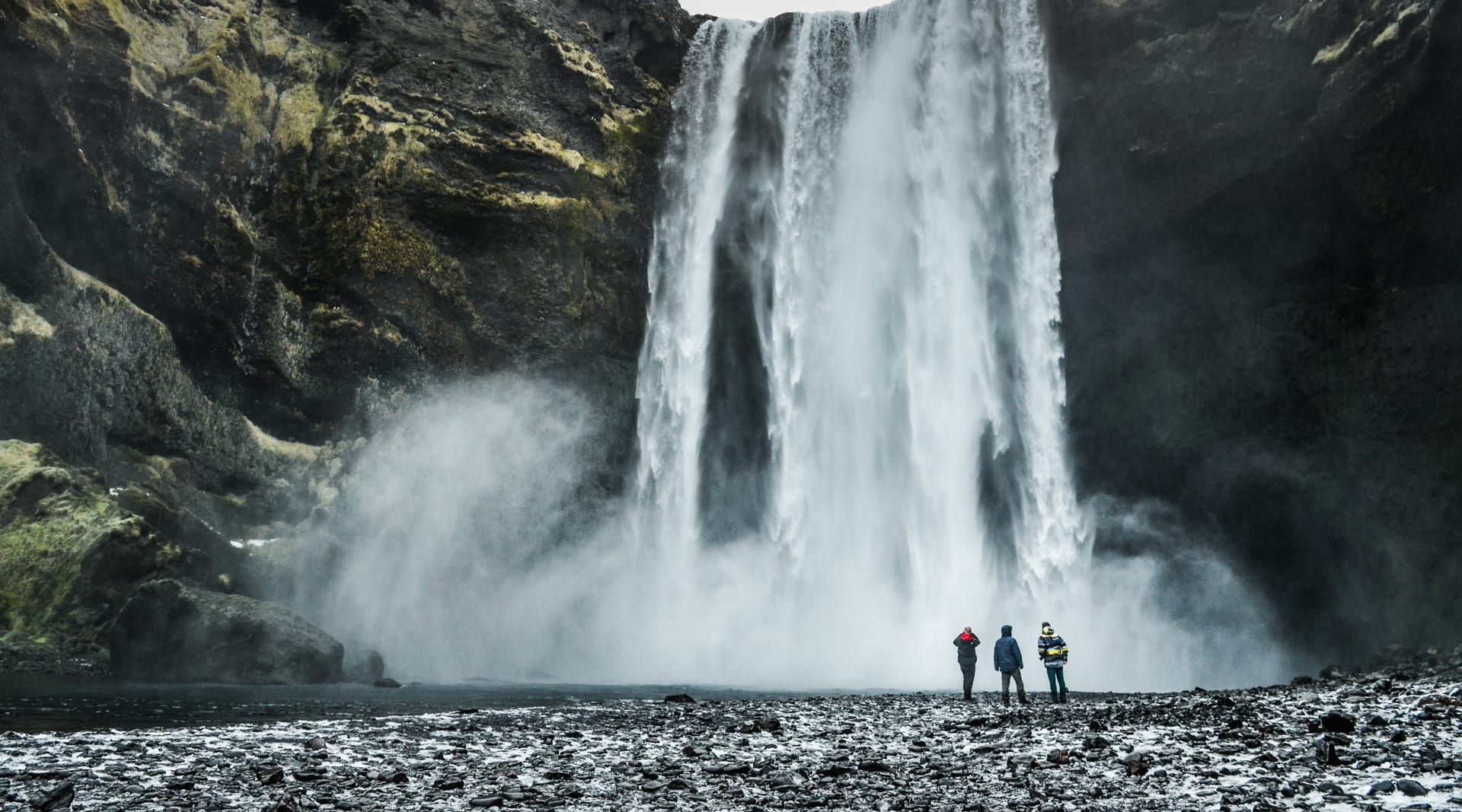 People standing next to Skogafoss waterfall