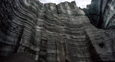 Thumbnail about Volcanic ash on a wall of ice by Katla Ice Cave in Iceland