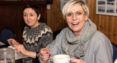 Thumbnail about A guest smiling while enjoying a cup of Icelandic soup