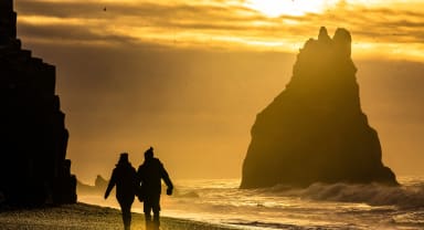 Thumbnail about People walking along the black sand beach during sunset