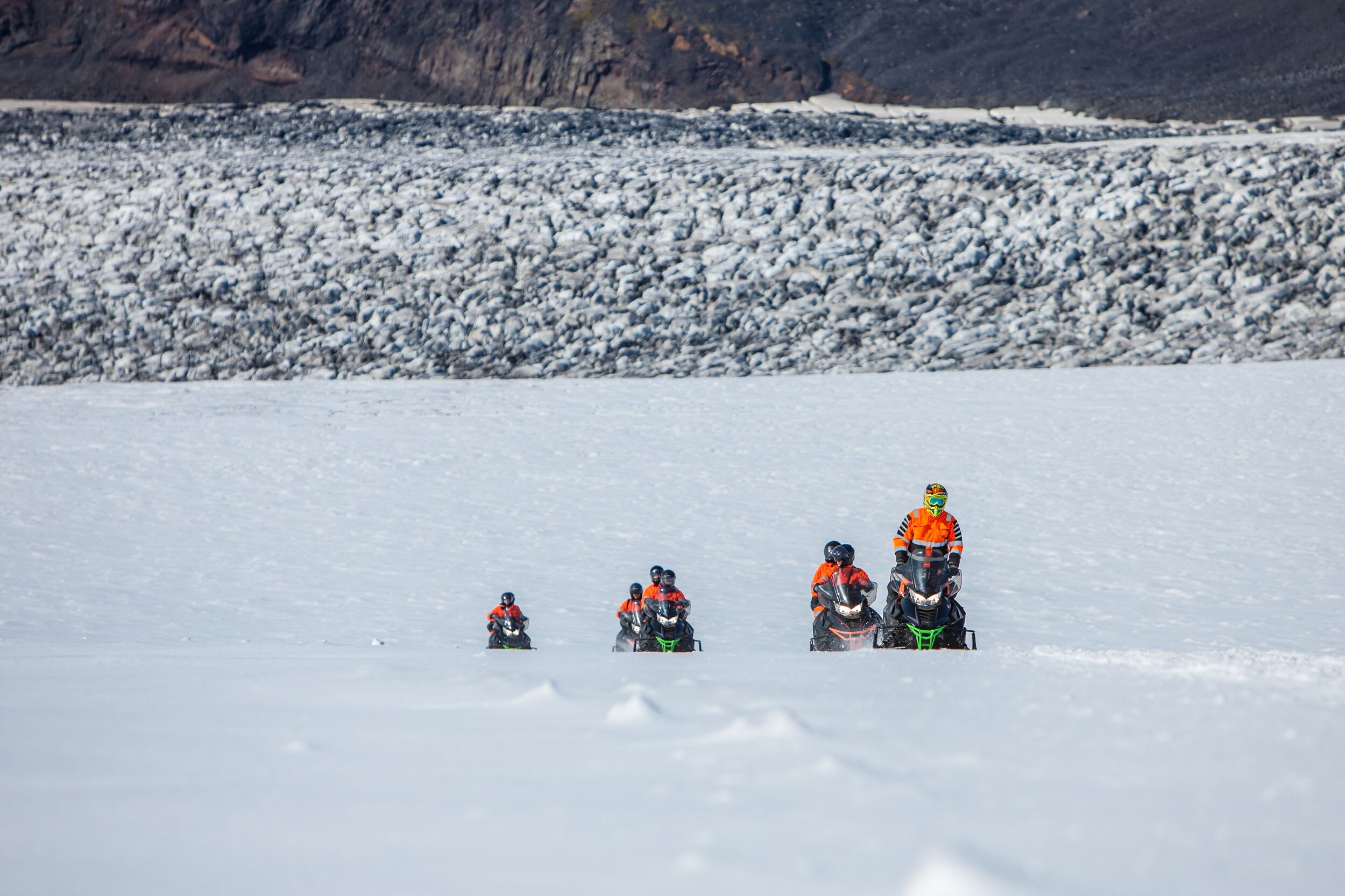 A group on snowmobiles traveling over a glacier