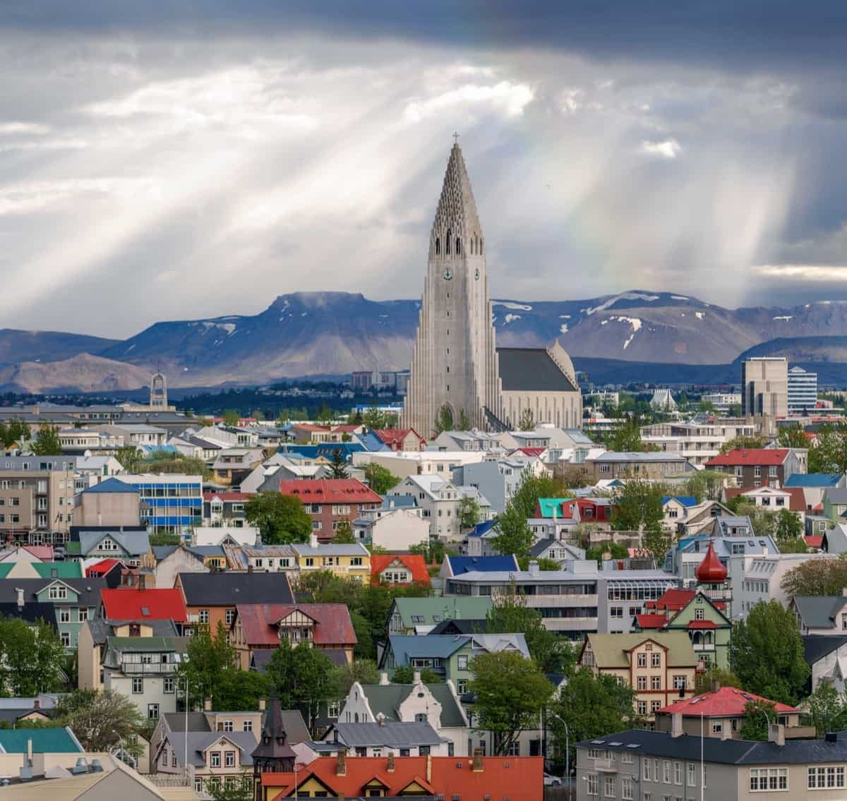 Reykjavík with Hallgrímskirkja church at the top and the sun coming through clouds above mt. Esja