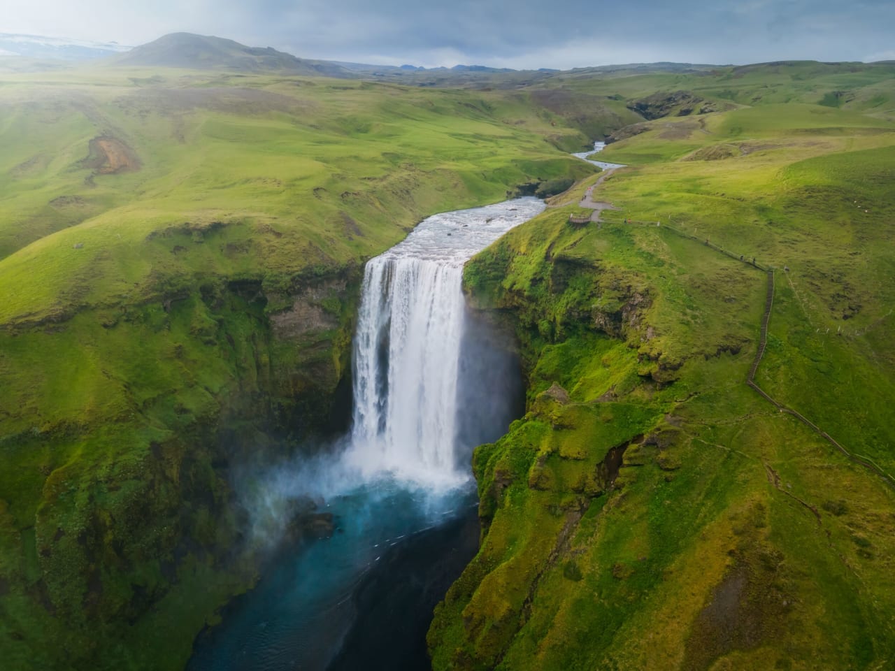Aerial shot of Skógafoss with its green surroundings