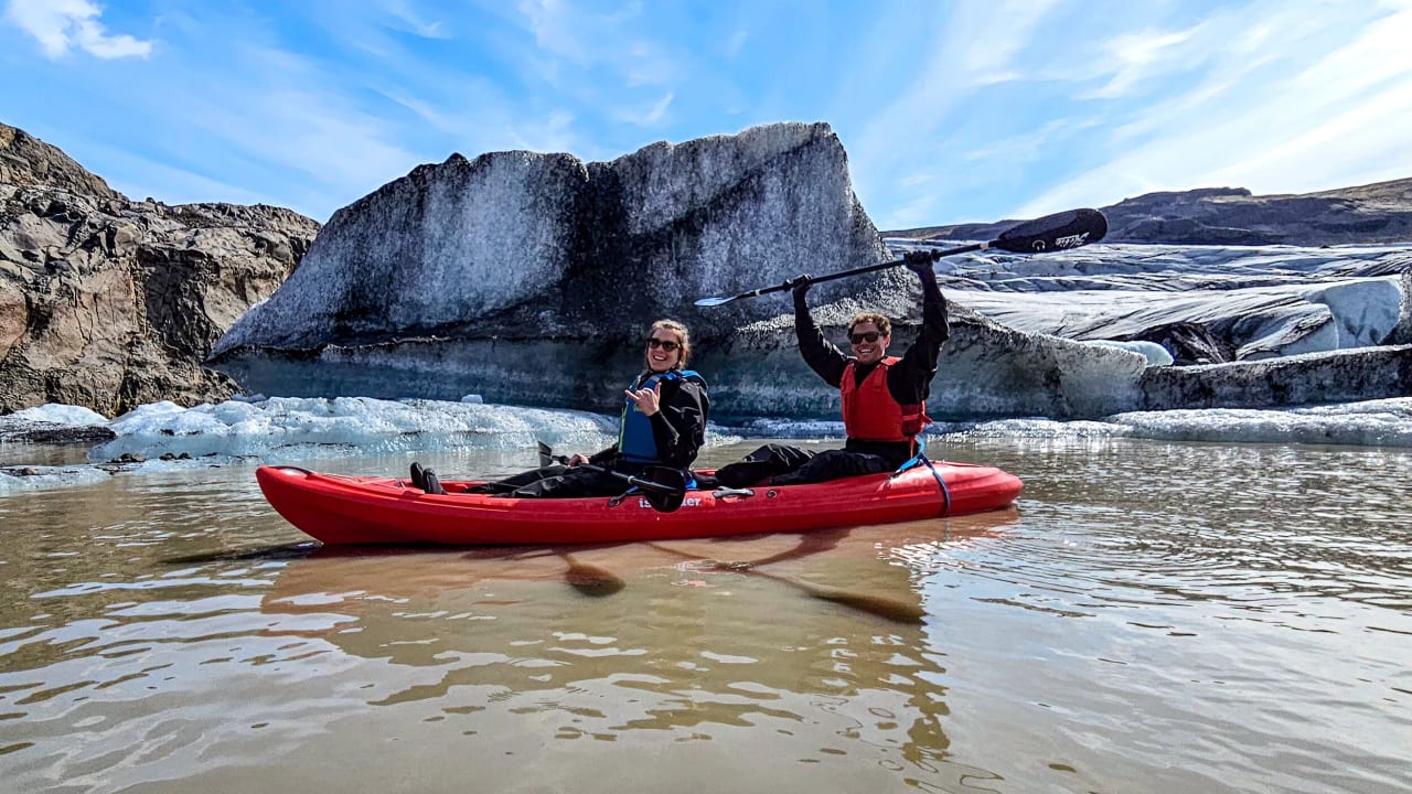 A smiling couple on a kayak in a glacier lagoon
