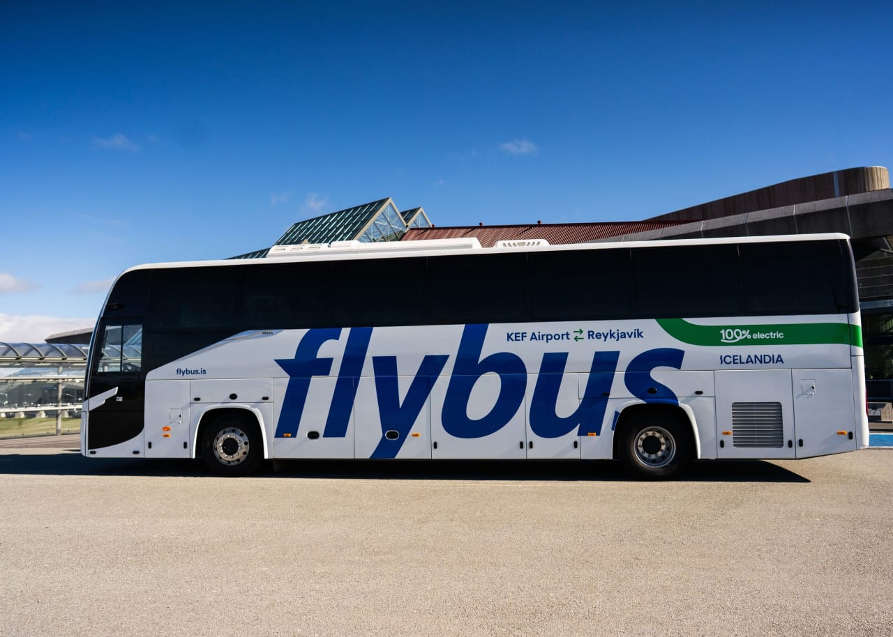The branded flybus vehicle saying 100% electric and Icelandia outside Keflavik Internation Airport