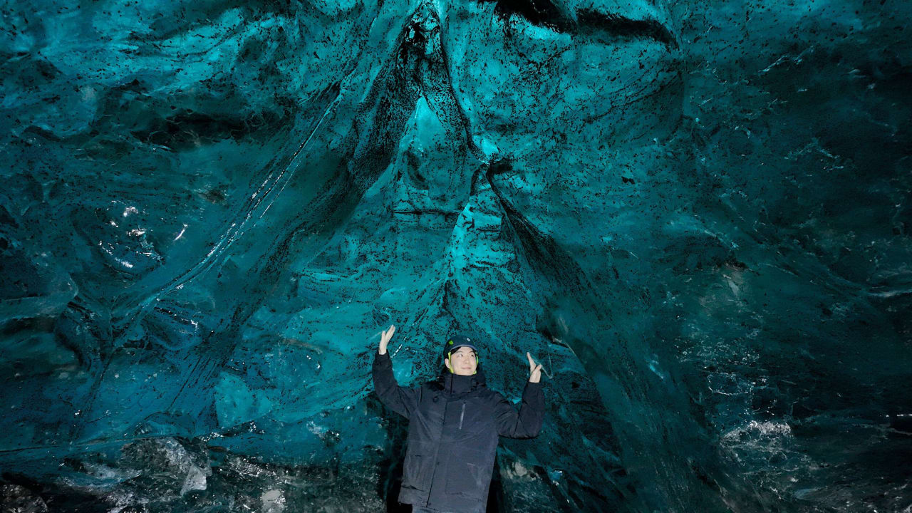 Tourist walking through a blue ice cave in Iceland