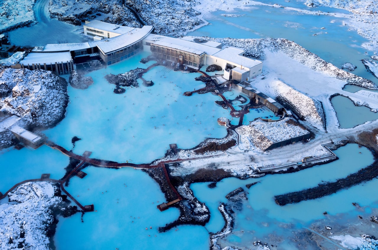 An aerial view of the blue lagoon in Iceland in Winter surronded by snow covered lava field.