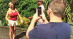 Thumbnail about A tourist is having her photo taken with the Mona monkey at Annandale waterfall.