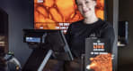 Thumbnail about A smiling staff member in a Lava Show t-shirt stands at the ticket and merchandise counter, ready to welcome guests.