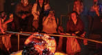 Thumbnail about Audience members sit in close proximity watching a large, glowing, freshly-cooled lava formation, with several people photographing the mome