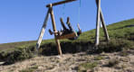 Thumbnail about Person swinging on a wooden swing overlooking a mountain landscape
