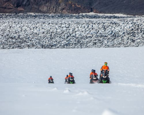 People crossing a glacier on snowmobiles