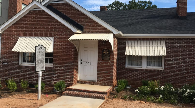 Small brick house with awnings over the door and windows, built in 1940.