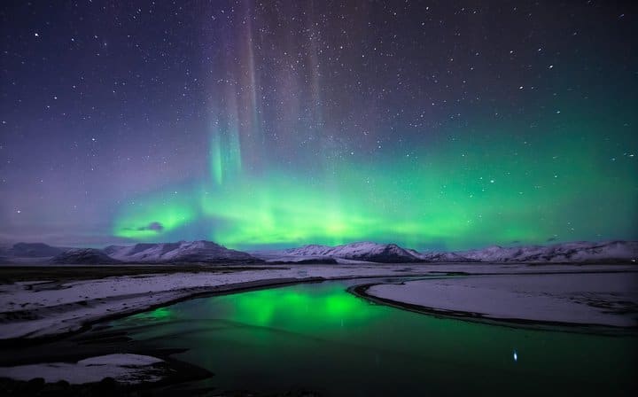 The spectacular show of the Northern Lights over a snow-covered Icelandic landscape