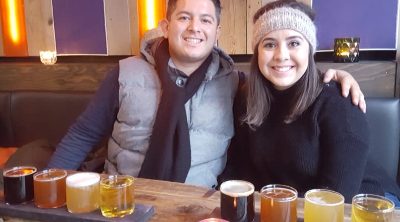 A couple smiling while sampling different beers.