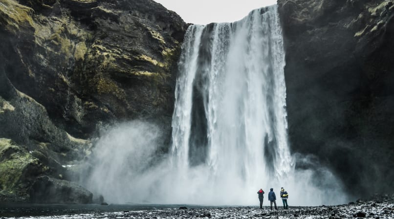Skogafoss waterfall with people standing next to falls