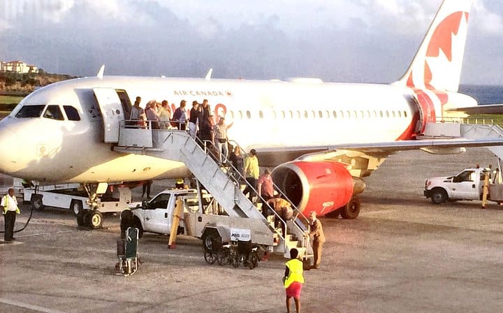 Passengers are getting out of a plane on the tarmac.